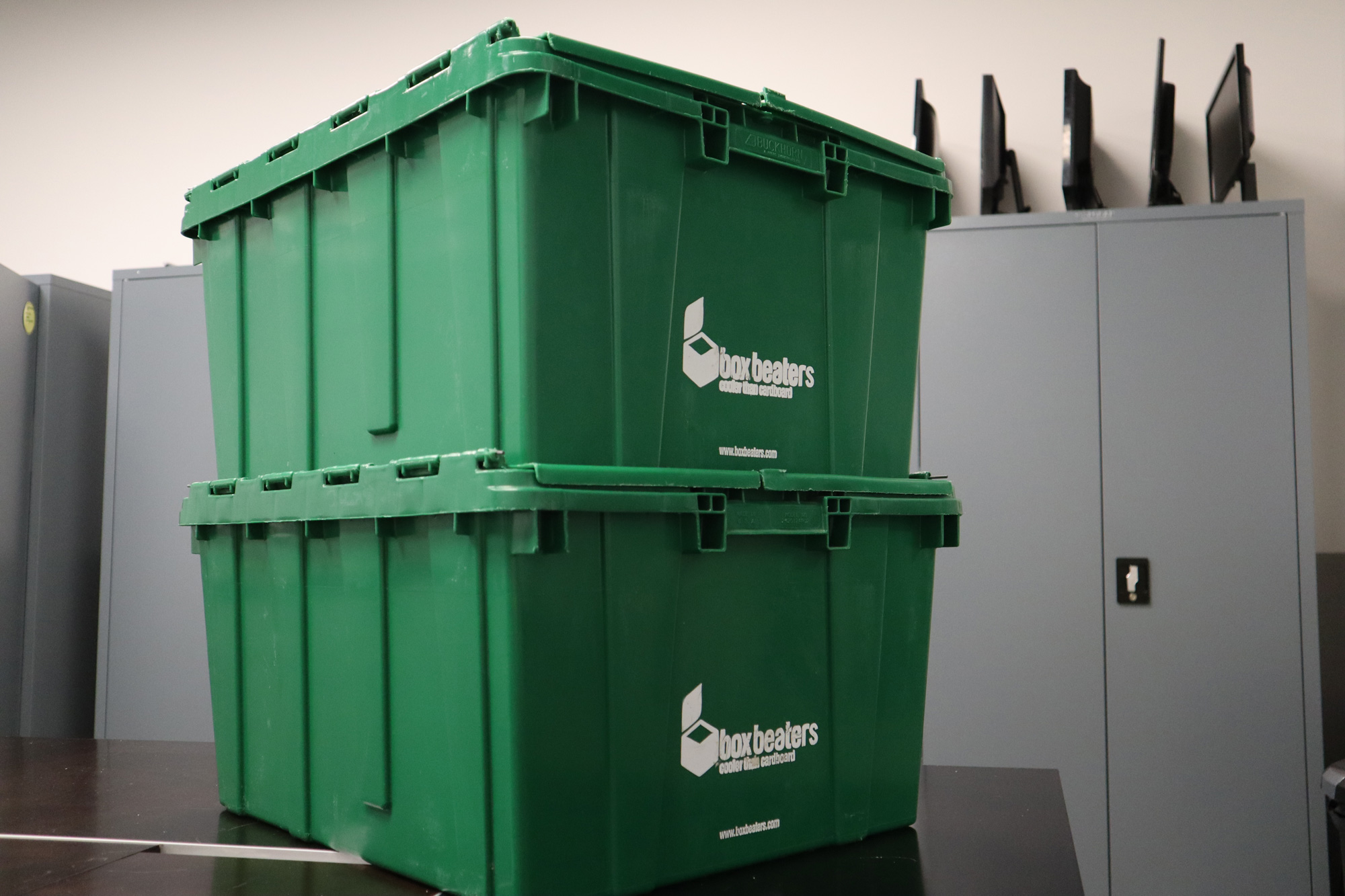 Two green bins stacked together in a conference room