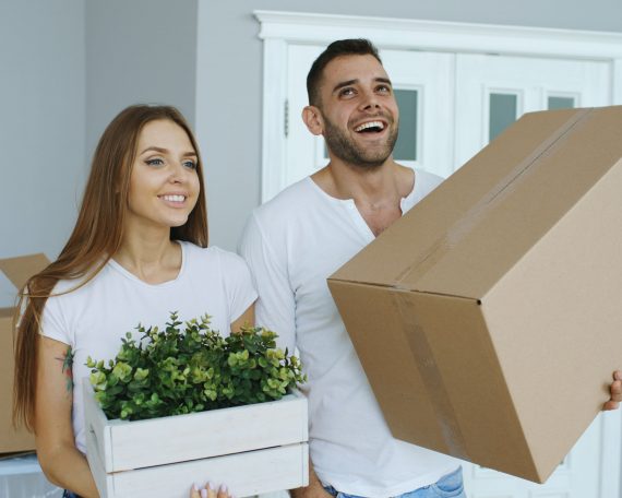 Couple holding an open first box as they move into a new home